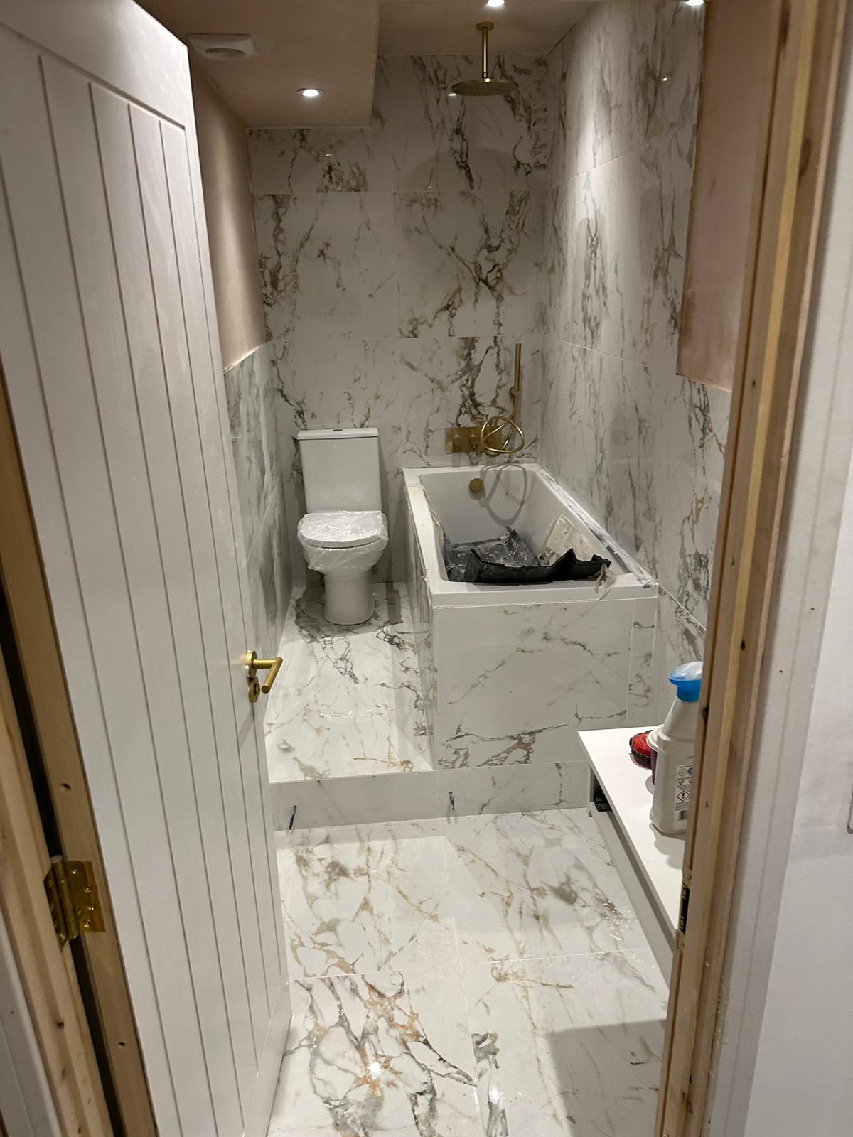 Bathroom marble effect tiling bath gold fittings